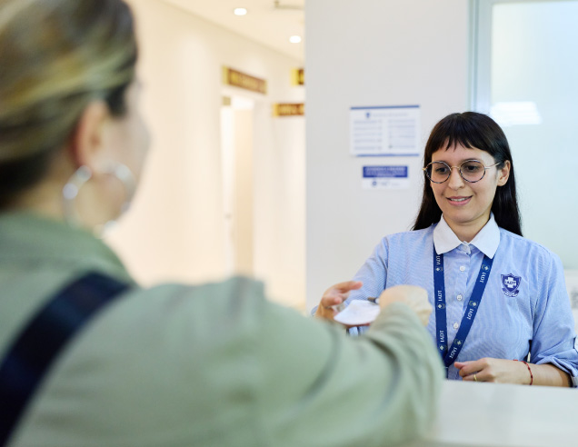Personal administrativo del IADT entregando documentación a una paciente en el área de recepción
