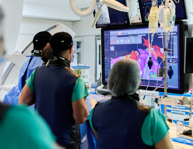 Equipo médico observando imágenes cardíacas durante un procedimiento de electrofisiología intervencionista en el IADT