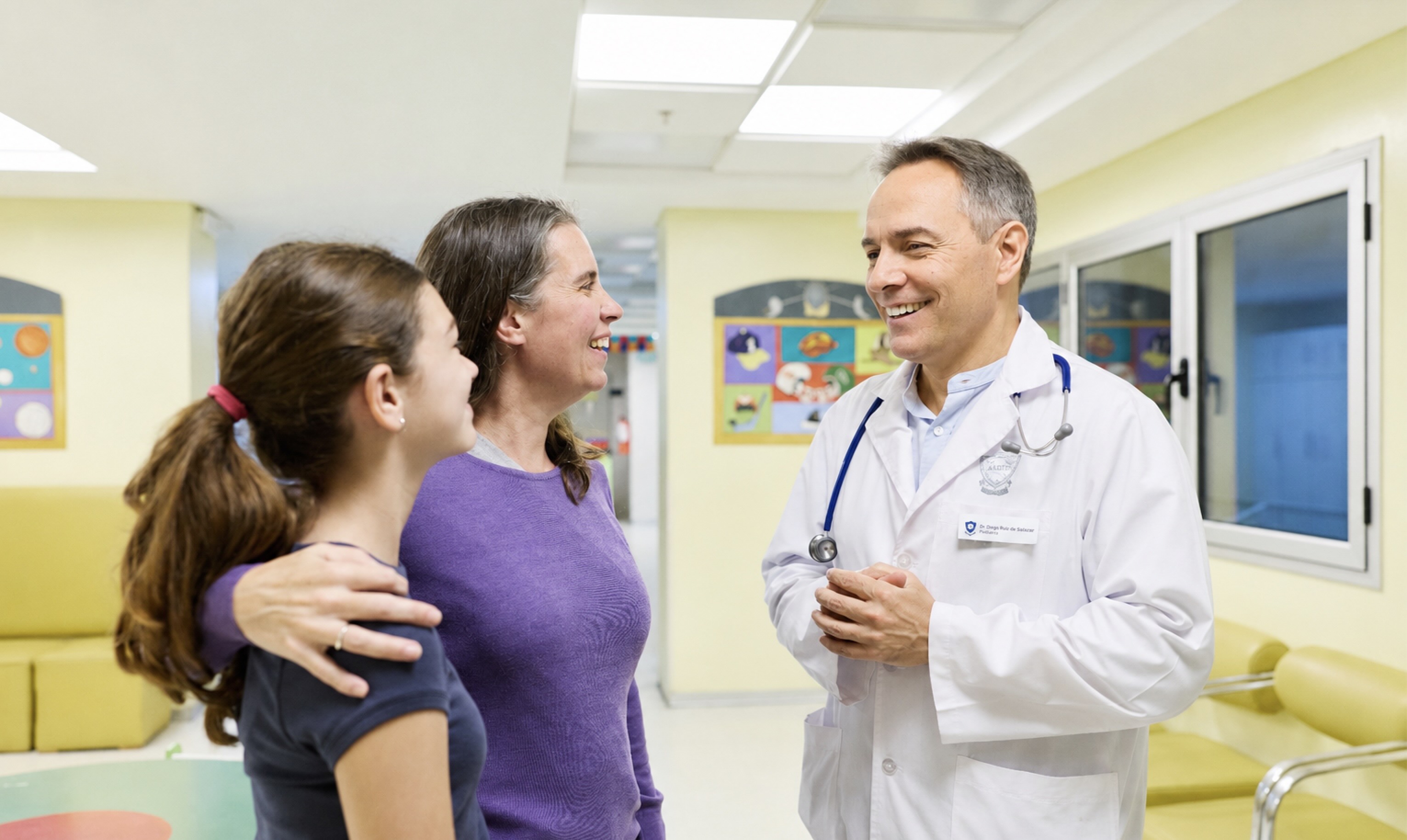Médico pediatra conversando con una paciente y su madre en el área de consultorios externos de Pediatría del IADT