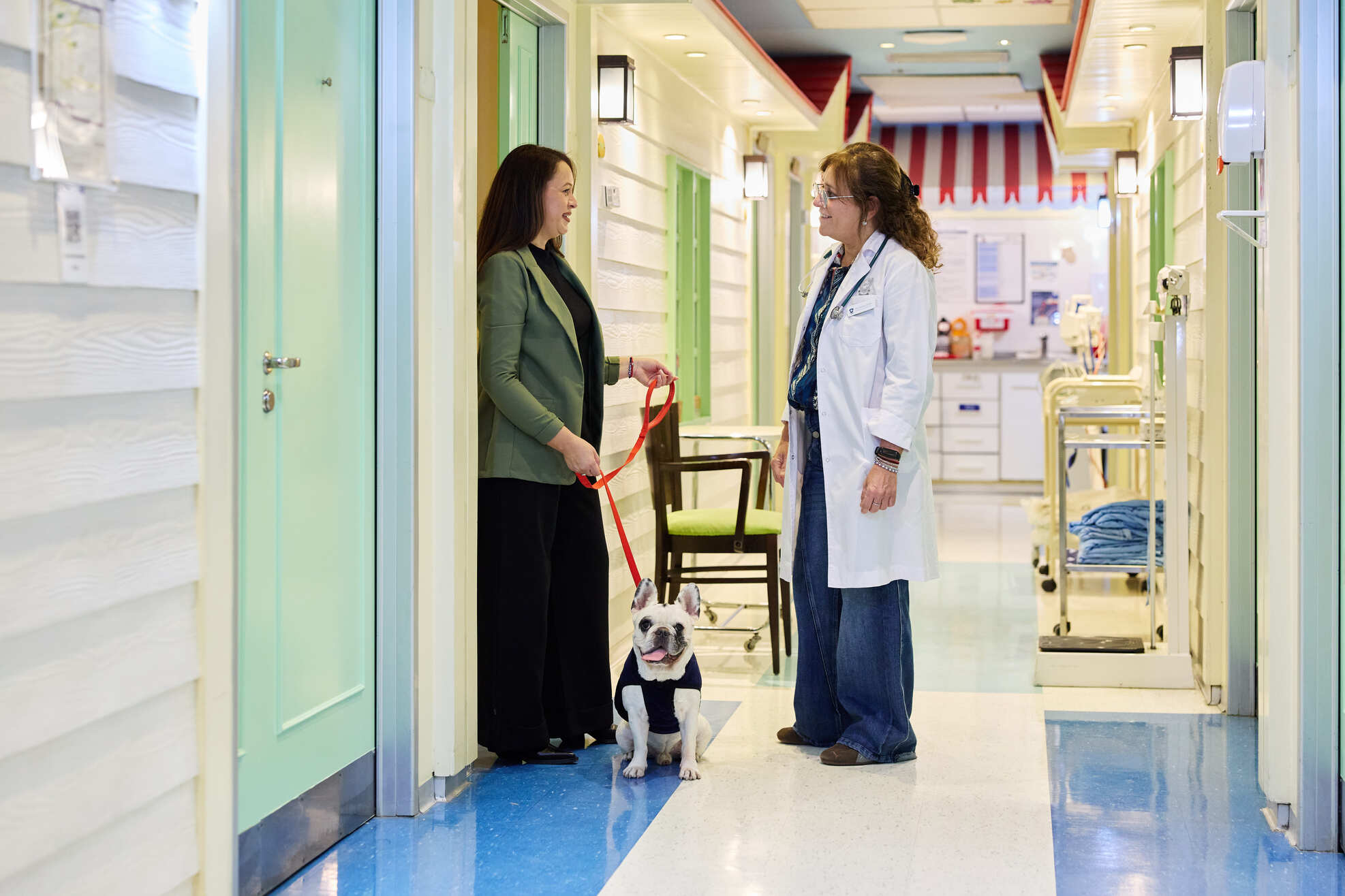 Profesional médica conversando con una familiar junto a una mascota en el área de Pediatría del IADT