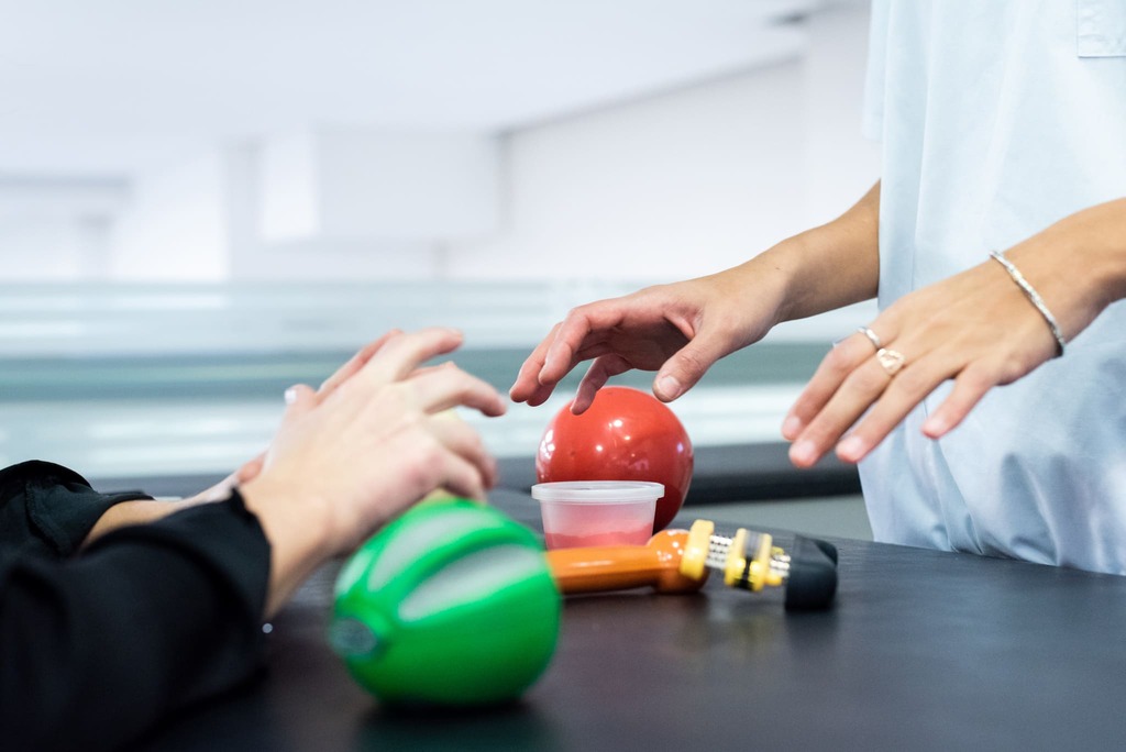 Profesional de la salud guiando ejercicios de motricidad y rehabilitación funcional con elementos terapéuticos