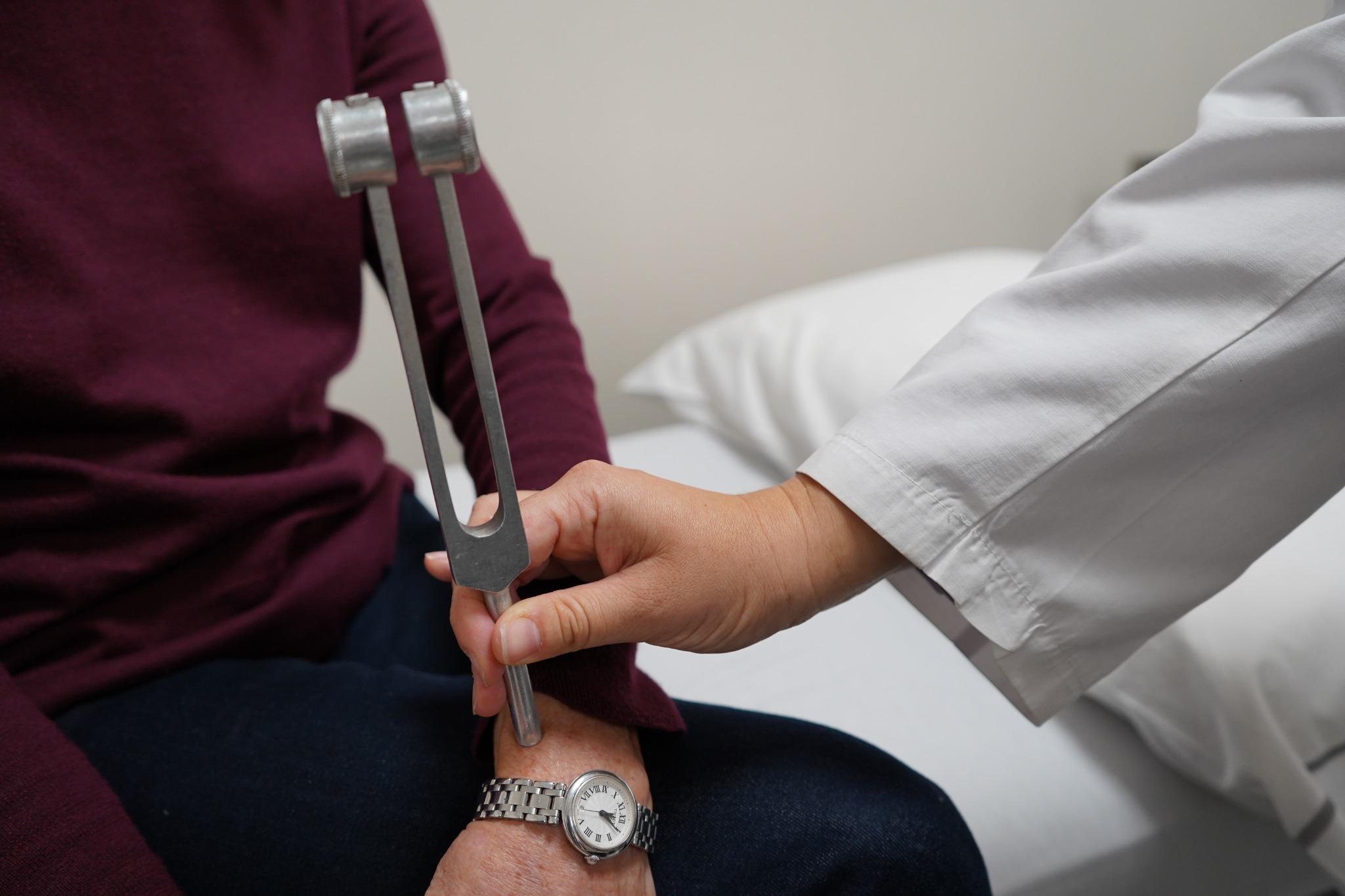 Médico realizando una prueba neurológica con diapasón durante la evaluación de una paciente en el IADT