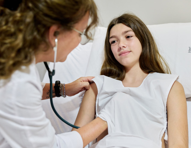 Médica pediatra realizando el control clínico de una paciente pediátrica en consultorio