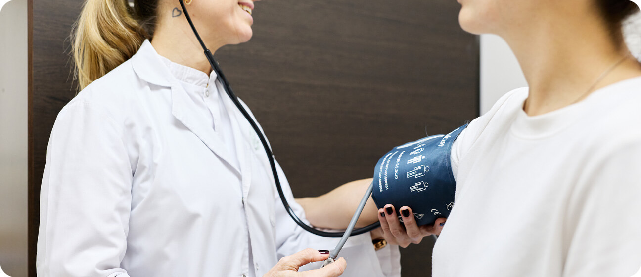 Médica realizando control clínico y toma de presión arterial a una paciente en consultorio del IADT