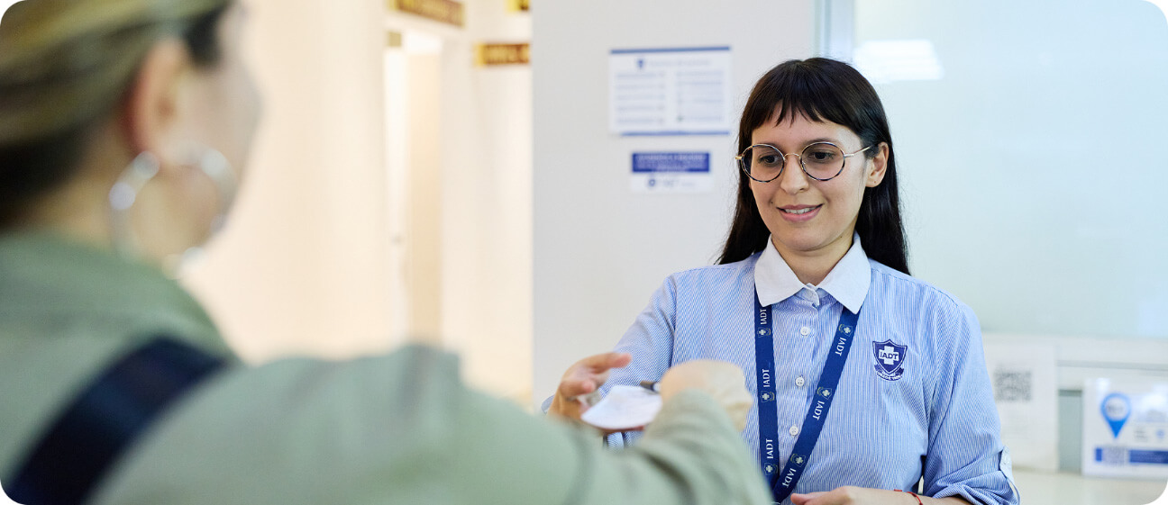 Personal administrativo del IADT entregando documentación a una paciente en el área de recepción